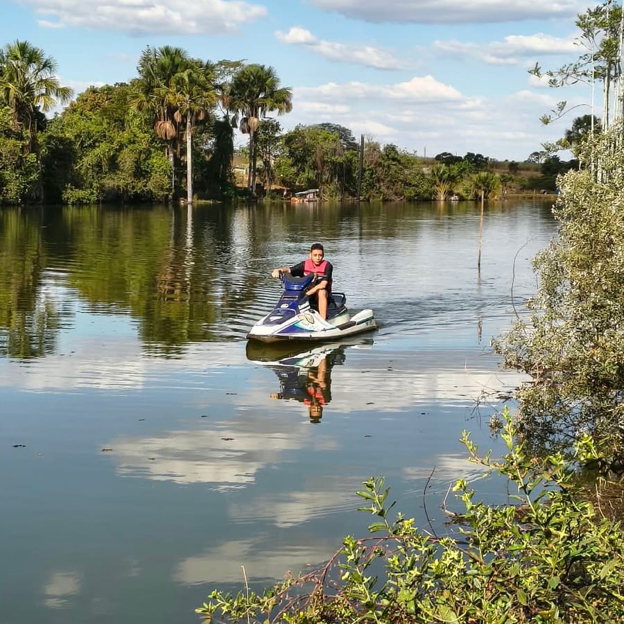 Jet ski no lago, com palmeiras e mata ao fundo