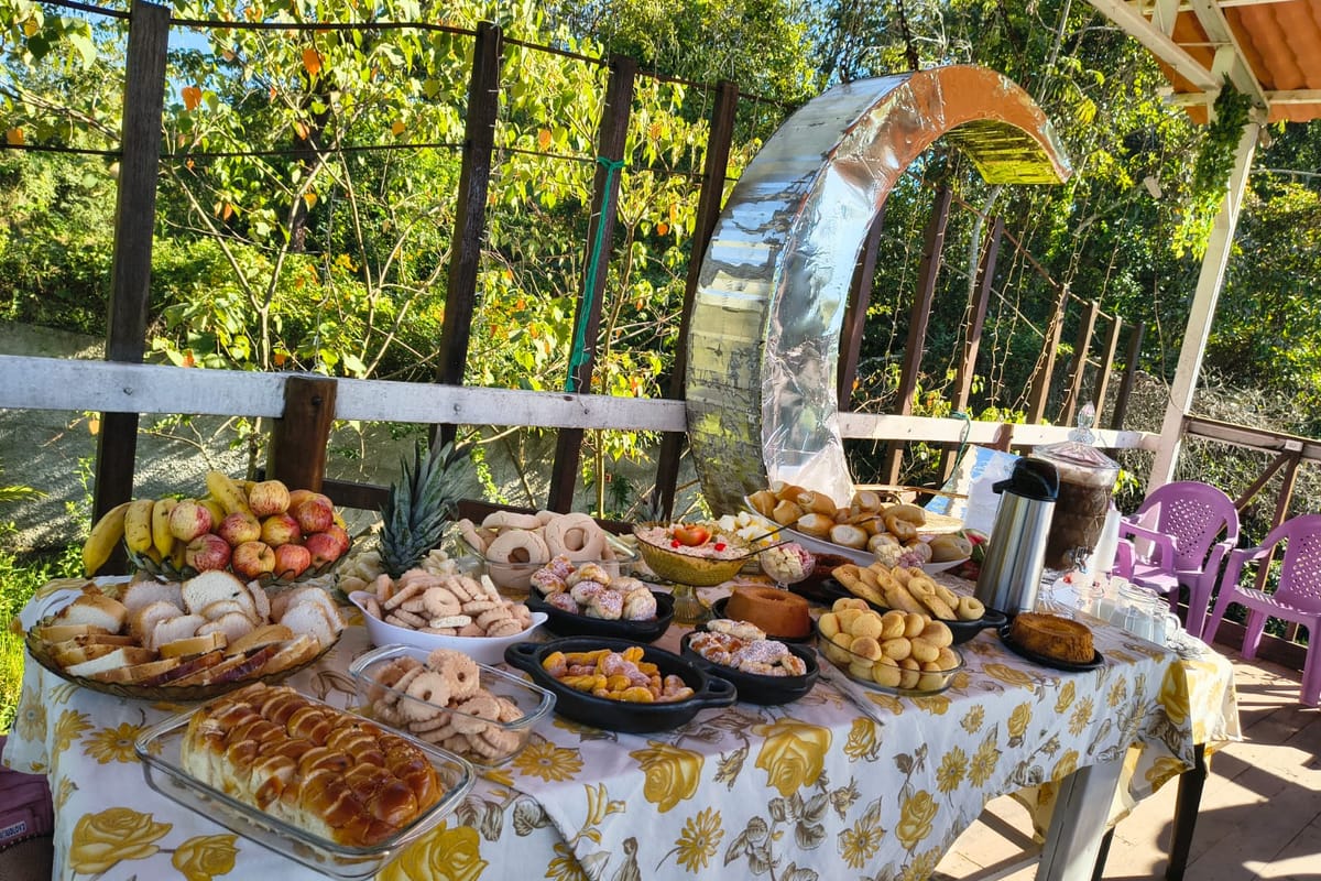 Mesa de café da manhã com pães, bolos, frutas e biscoitos