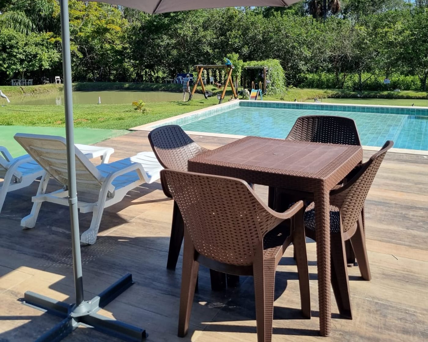Piscina do retiro com o lago, o gramado e a mata ao fundo