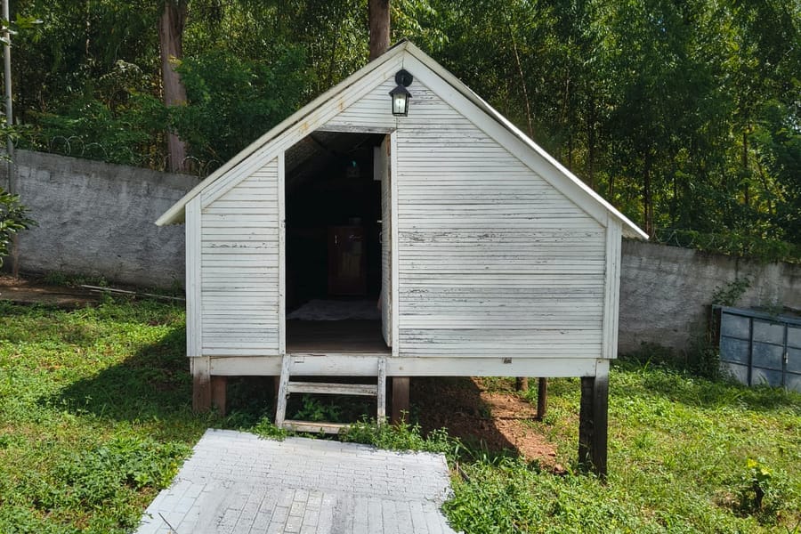 Cabana Branca, de madeira pintada de branco, no gramado
