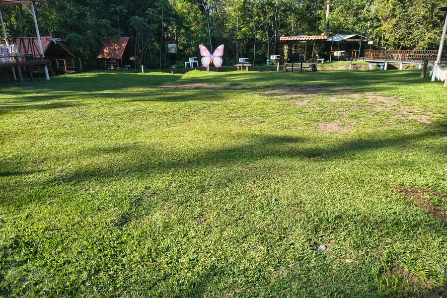 Gramado do camping com quiosques ao fundo