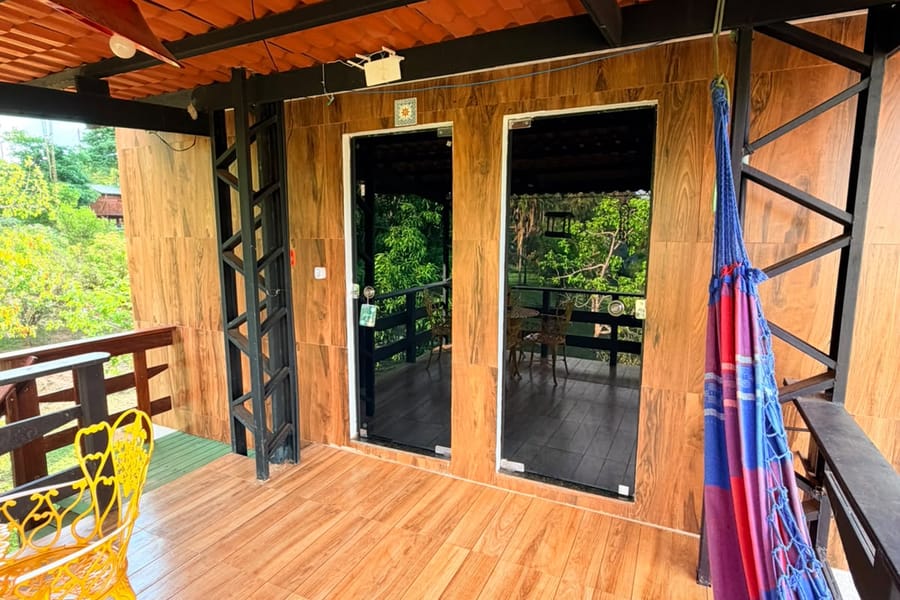 Varanda de madeira do Apartamento Sobrado 1, com rede e cadeiras